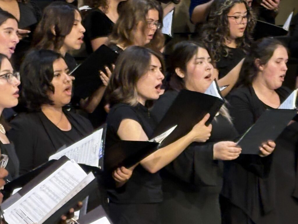 Sopranos and altos singing from black folders